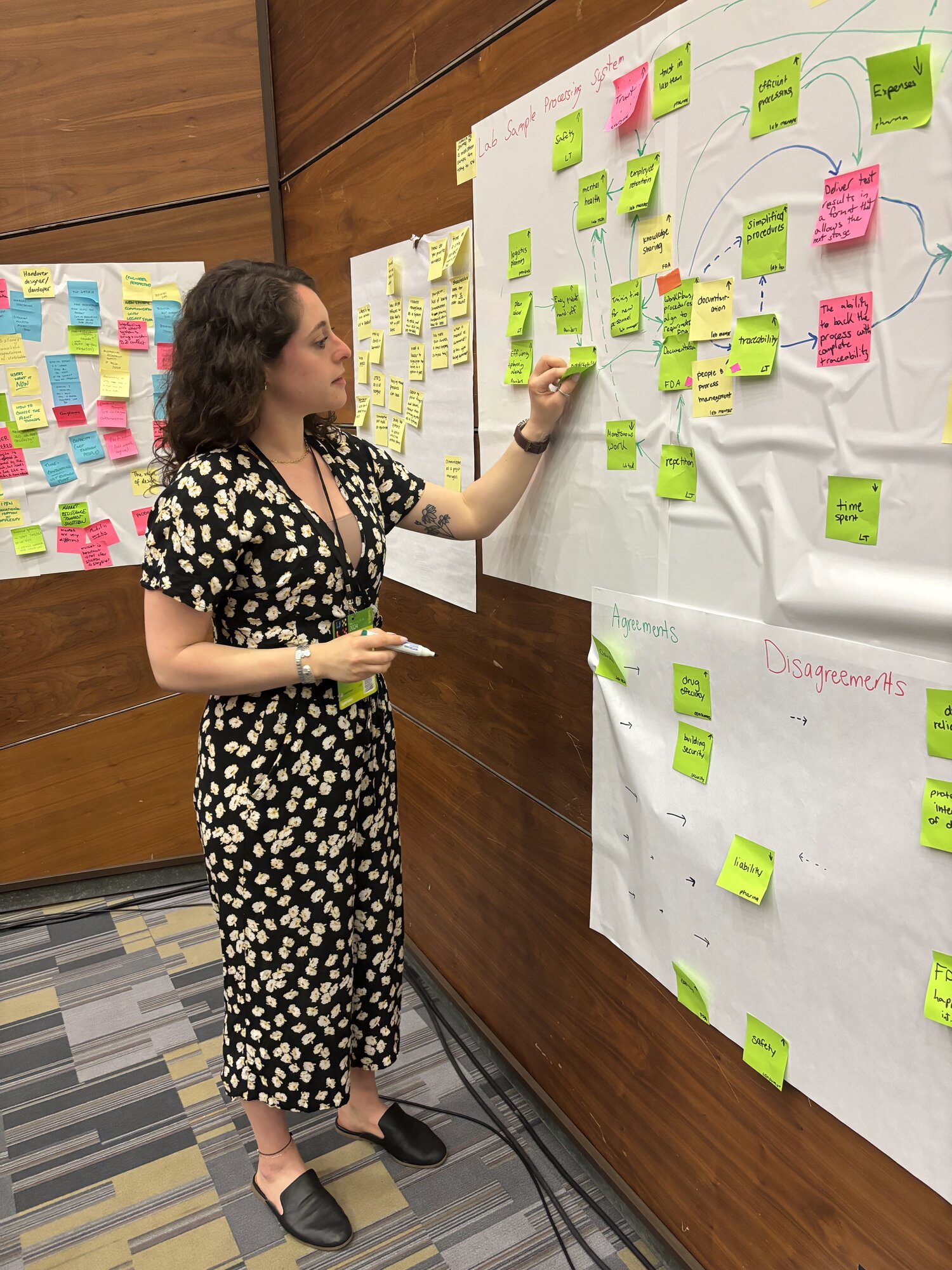 Suzie Duquette mapping research findings on a sticky-note synthesis wall during a workshop